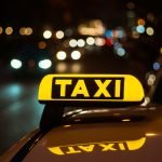 Yellow and black sign of Taxi placed on top of a car at night Taxi Lasarte-Oria